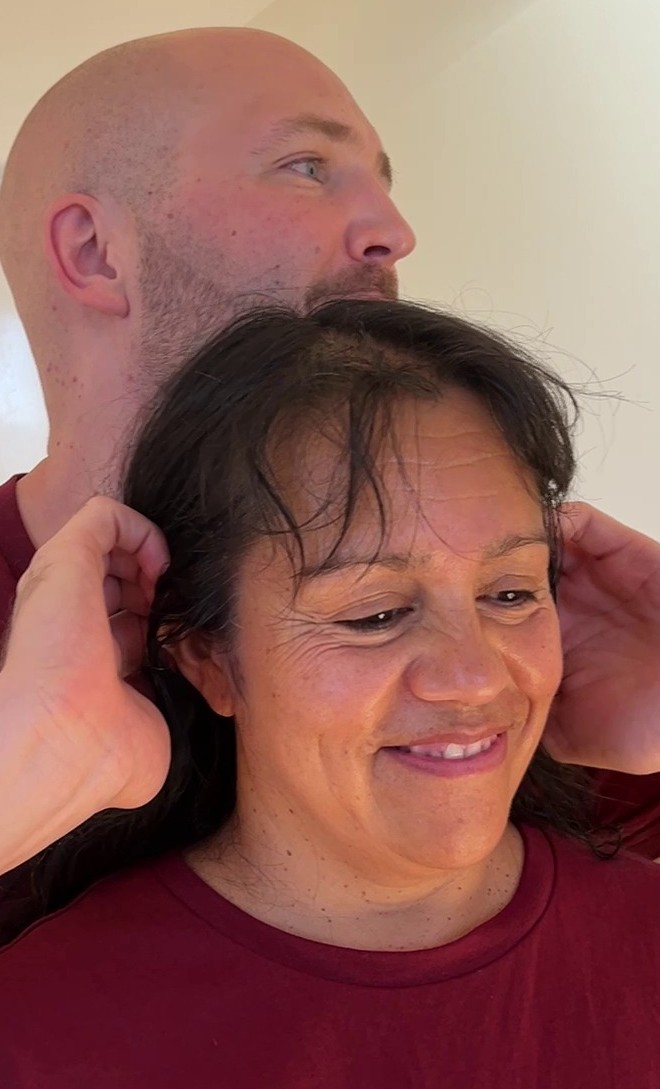 Eine lachende Frau, hinter ihr hält Maximilian ruhig ihren Kopf mit beiden Händen.